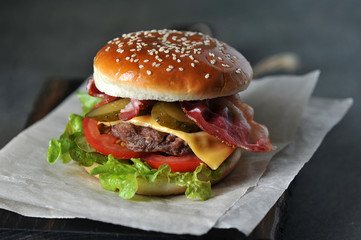 Cheeseburger with bacon close-up. Dark background. Macro shooting.
