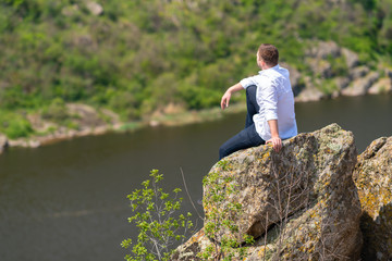 Fototapeta na wymiar Man sitting on a rock above a wide river