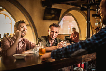 Cheerful friends drinking draft beer in a pub