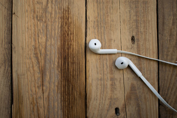 white telephone headphones on a wooden desktop