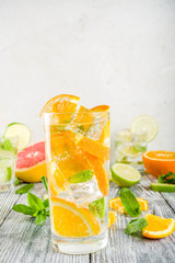 Summer refreshment drinks. Four types of citrus lemonade or mojito cocktail - orange, lime, lemon, pink grapefruit. Infused citrus water. On a wooden white background,
