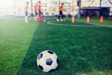 Obraz na płótnie Canvas football on green artificial turf with blurry soccer team training