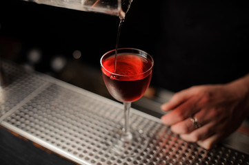Cherry drops in cocktail from special tongs