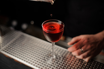 Cherry falls in a cocktail from professional tongs
