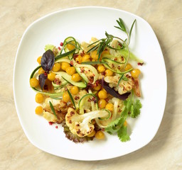 Roasted cauliflower with chickpeas, zucchini noodles and rosemary, salad, top view