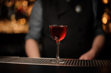 Alcohol drink with cherry with bartender behind