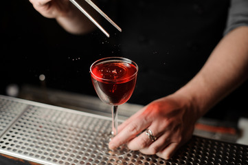 Bartender dropping cherry in an alcohol drink