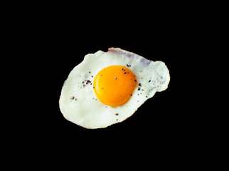 Fried egg sunny side up with pepper isolated on black background