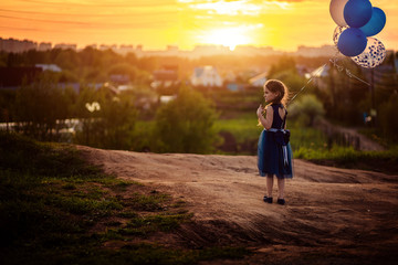 little girl in blue dress with balloons at sunset © pliona