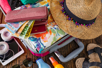 Suitcase preparation for a summer holiday and wallet with money