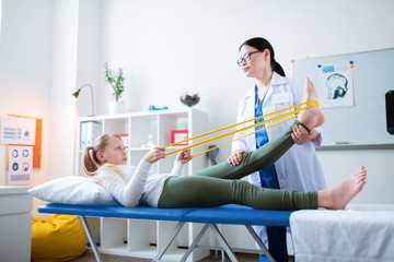 Focused dark-haired doctor in white robe involved in exercising