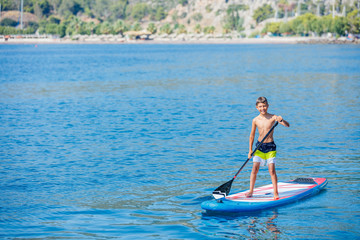 Paddle boarder. Child boy paddling on stand up paddleboard. Healthy lifestyle. Water sport, SUP surfing tour