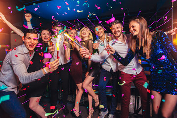 Group of friends partying in a nightclub and toasting drinks.