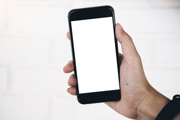 Mockup image of woman's hand holding and using white mobile phone at outdoor with copy space,blank screen for text.concept for business,people communication,technology electronic device.