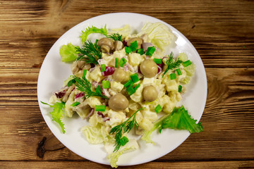 Potato salad with marinated mushrooms, eggs, red onion and mayonnaise on wooden table