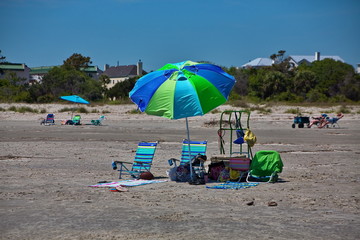 Empty colorful beach chairs in the sand under an umbrella