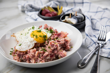 Norddeutscher Hamburger Labskaus mit Rindfleisch Corned Beef, Rote Beete, Kartoffeln, Saure Gurken, Spiegelei und Rollmops auf Teller