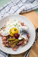 Norddeutscher Hamburger Labskaus mit Rindfleisch Corned Beef, Rote Beete, Kartoffeln, Saure Gurken, Spiegelei und Rollmops auf Teller
