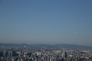 Plane and view of Osaka from the Umeda Building at sunset on a sunny day