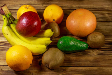 Assortment of tropical fruits on wooden table. Still life with bananas, mango, oranges, avocado, grapefruit and kiwi fruits