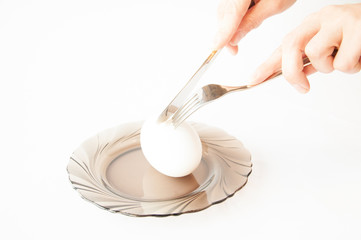 big goose egg on a plate. In the hands of the knife and fork hold the egg.