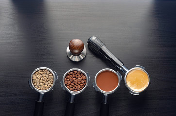 four holders with green, roasted, ground, and hot coffee and tamper, equipment for making freshly...