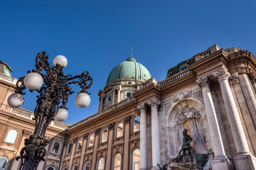 Fototapeta na wymiar Hungary, Budapest, Buda, Hunyadi Udvar: Famous facade of Royal Palace at Castle Hill district above the city center of the Hungarian capital with vintage lantern and blue sky - concept architecture.