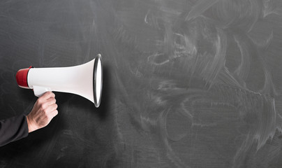 hand holding red and white megaphone against chalkboard template