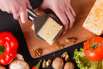 young woman slicing cheese in a gray apron
