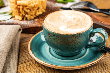 Cappuccino Cup with latte on wooden background. Beautiful foam, green ceramic Cup.