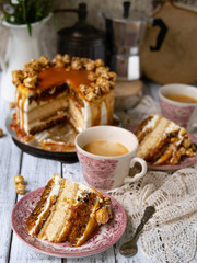 Carrot cake with salted caramel and cheesecake inside, decorated with popcorn and caramel. A slice of cake with a cup of coffee, retro style, vintage. Selected focus, close up