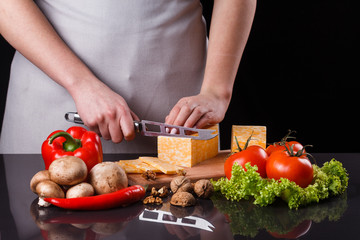 young woman slicing cheese in a gray apron
