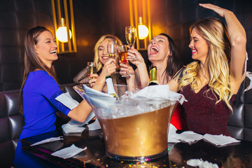  Happy women clinking champagne glasses and celebrating at night club