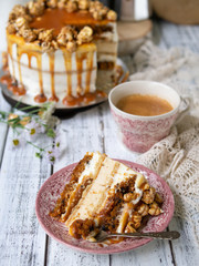 Carrot cake with salted caramel and cheesecake inside, decorated with popcorn and caramel. A slice of cake with a cup of coffee, retro style, vintage. Selected focus, close up