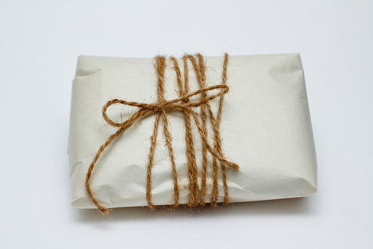 Old paper parcel with tie on white background.