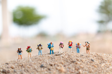 Miniature people : Traveler with backpack walking  on sand