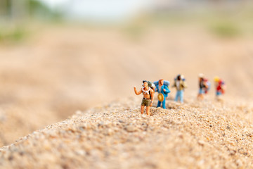 Miniature people : Traveler with backpack walking  on sand