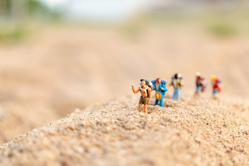 Fototapeta na wymiar Miniature people : Traveler with backpack walking on sand