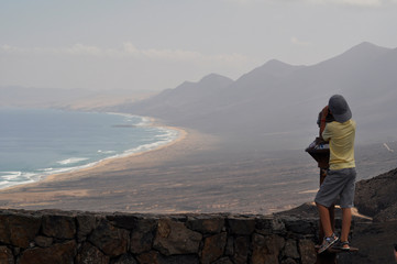 Boy on top of mountain looking at the ocean coastline. Cofete, Fuerteventura Canary islands