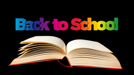 Back to school. Open book on black background. Text