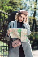 Cute young beautiful curly confused caucasian travelling woman reading a map.