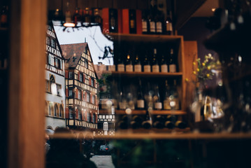 Colmar, France -  May 2, 2019: Colorful traditional french houses are reflected in a show-window of wine shop, Colmar, France