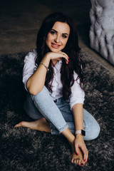 Photo session of a young brunette in jeans and a white shirt.