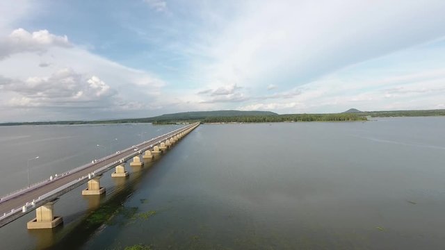 Slow, rising aerial view across vehicles on Thep Sada Bridge the Deja Vu Bridge, 2-lane reinforced concrete bridge across Lam Pao Dam at Kalasin,Thailand