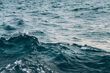 Fototapeta na wymiar ripples on blue sea water with white foam , natural sea background