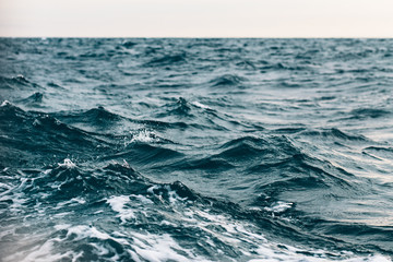 Fototapeta premium ripples on blue sea water with white foam , natural sea background