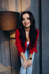 Obraz na płótnie Canvas Photo session of a young brunette in jeans and a red jacket.