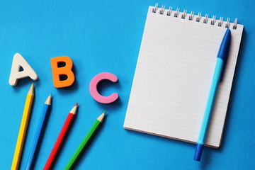 ABC-the first letters of the English alphabet on a blue background. Notebook and pen. Empty space for text. Learn foreign languages.