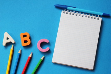 ABC-the first letters of the English alphabet on a blue background. Notebook and pen. Empty space for text. Learn foreign languages.