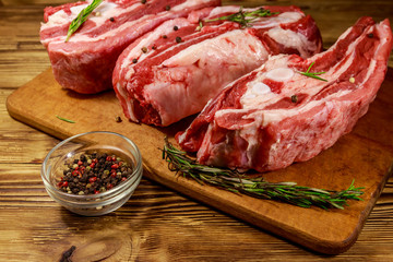 Raw pork ribs with spices and rosemary on wooden table